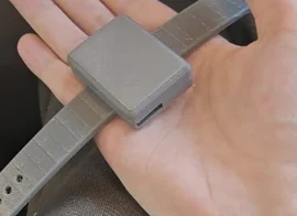 CareTether V2 enclosed wearable and strap resting in a hand.