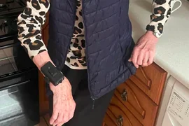 CareTether worn on a user-testing participant's wrist in a kitchen; only the torso and hands are shown.