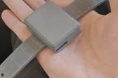 CareTether V2 enclosed wearable and strap resting in a hand.