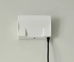 A NexaSense radar unit installed on a wall with its power cable connected.